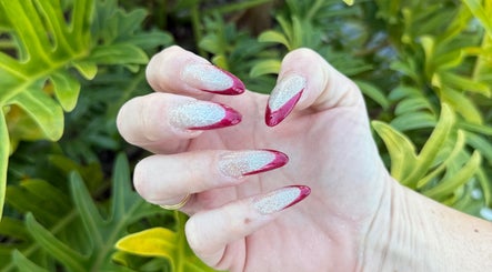 Elegant red and silver glitter nails at Beauty Point GC, Robina, Queensland, AU amidst lush greenery.