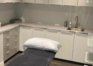 Modern treatment room at Beauty by Lucy, London, England, GB, with sleek cabinets and a plush treatment bed.