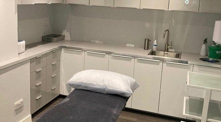 Modern treatment room at Beauty by Lucy, London, England, GB, with sleek cabinets and a plush treatment bed.