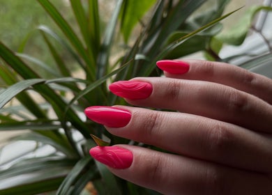 Ongles rose vif à L'Nails Beauty, Sarrebourg, Grand Est, FR, avec une plante en arrière-plan.