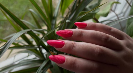 Ongles rose vif à L'Nails Beauty, Sarrebourg, Grand Est, FR, avec une plante en arrière-plan.