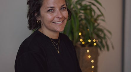 Personne souriante à Sanación bien-être, Seyssinet-pariset, Auvergne-rhône-alpes, FR avec plante lumineuse en arrière-plan.