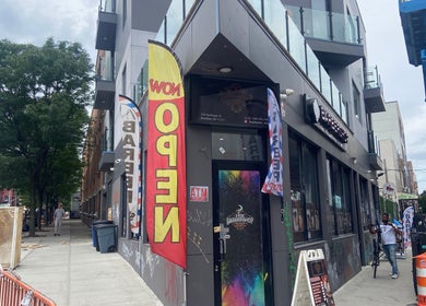 Street view of Eraylin ‘FadeByE’ barber shop, New York, New York, US, with colorful flags at the entrance.
