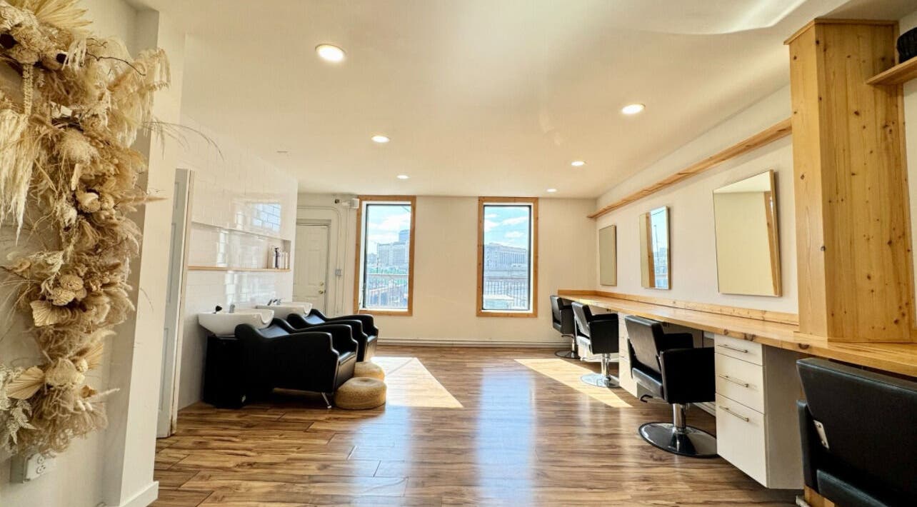 Bright, stylish salon interior at KC Braiding Bar in Kansas City, Missouri with modern chairs and wooden flooring.