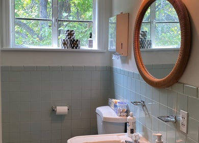 Cozy bathroom at Zephyr Massage and Bodywork, North Little Rock, Arkansas, US with a round mirror and soft lighting.