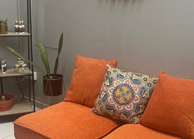 Cozy lounge area at Follicles Laser Aesthetic Spa in Castries, LC with orange seating and decorative plants.