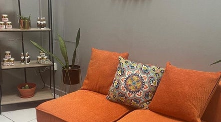 Cozy lounge area at Follicles Laser Aesthetic Spa in Castries, LC with orange seating and decorative plants.