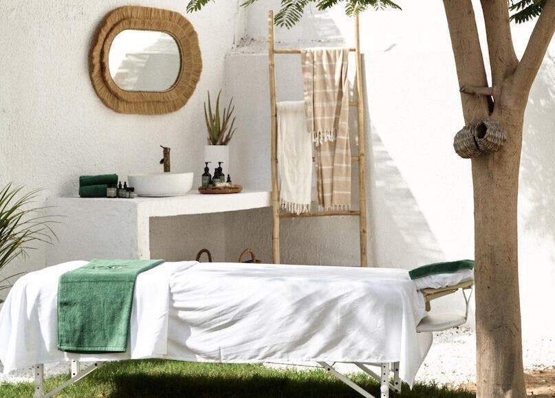 Outdoor massage setup at Raaha Wellness - Home Service, Dubai, AE, with green towel and tranquil surroundings.