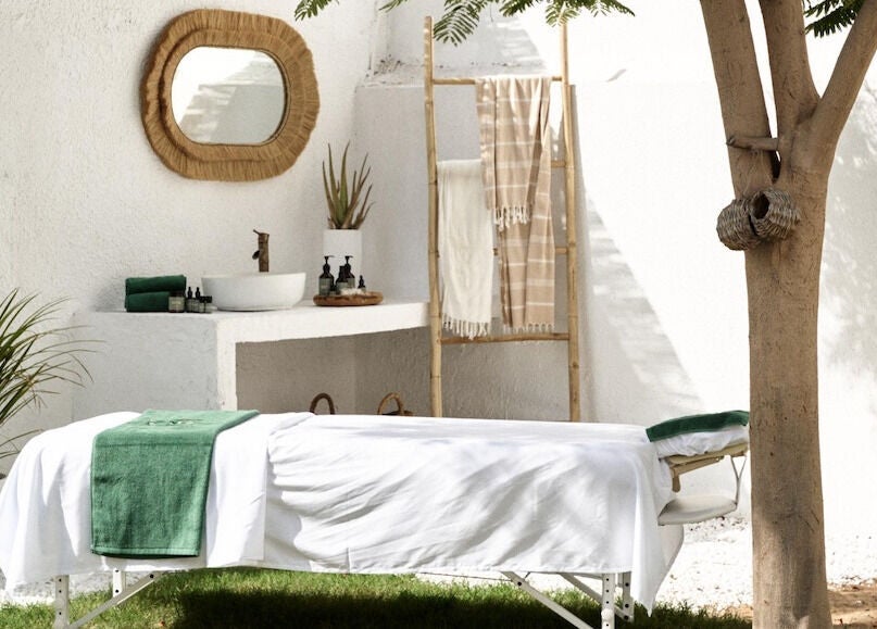 Outdoor massage setup at Raaha Wellness - Home Service, Dubai, AE, with green towel and tranquil surroundings.