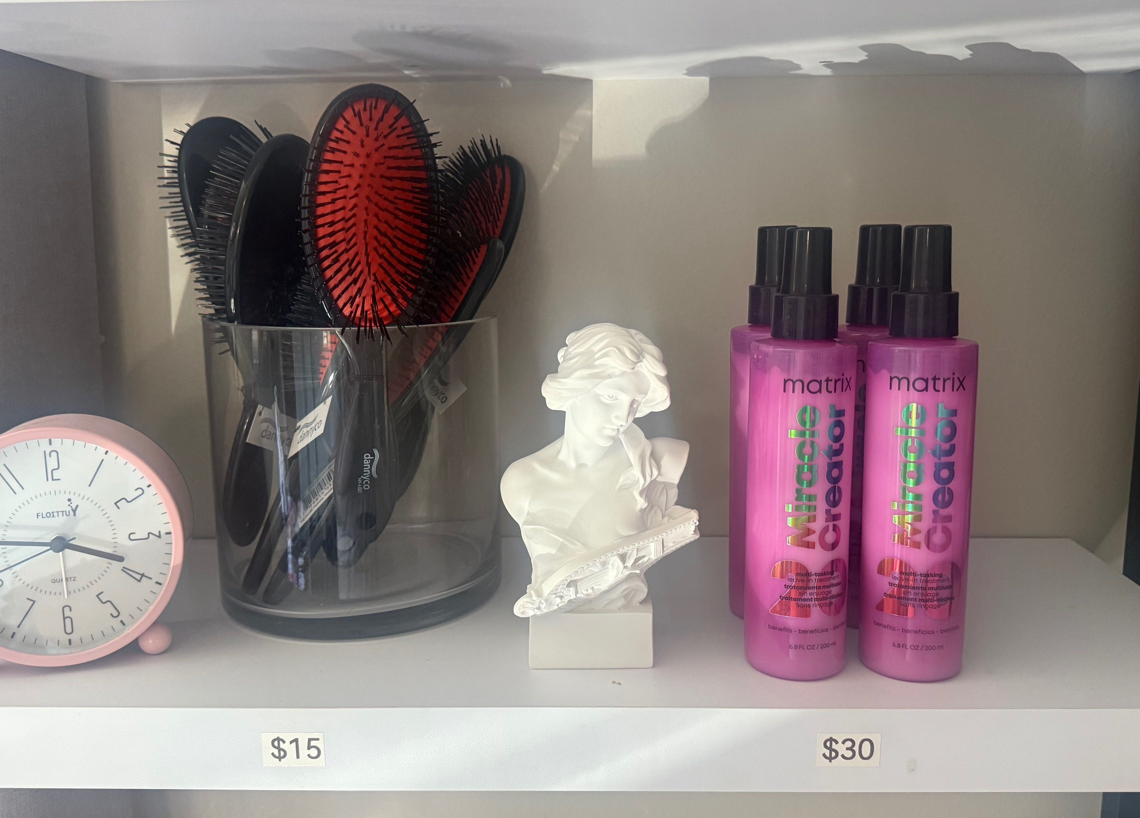 Beauty essentials at Nano Extensions by Chantelle in London, Ontario, CA. Hairbrushes, clock, and styling products on display.