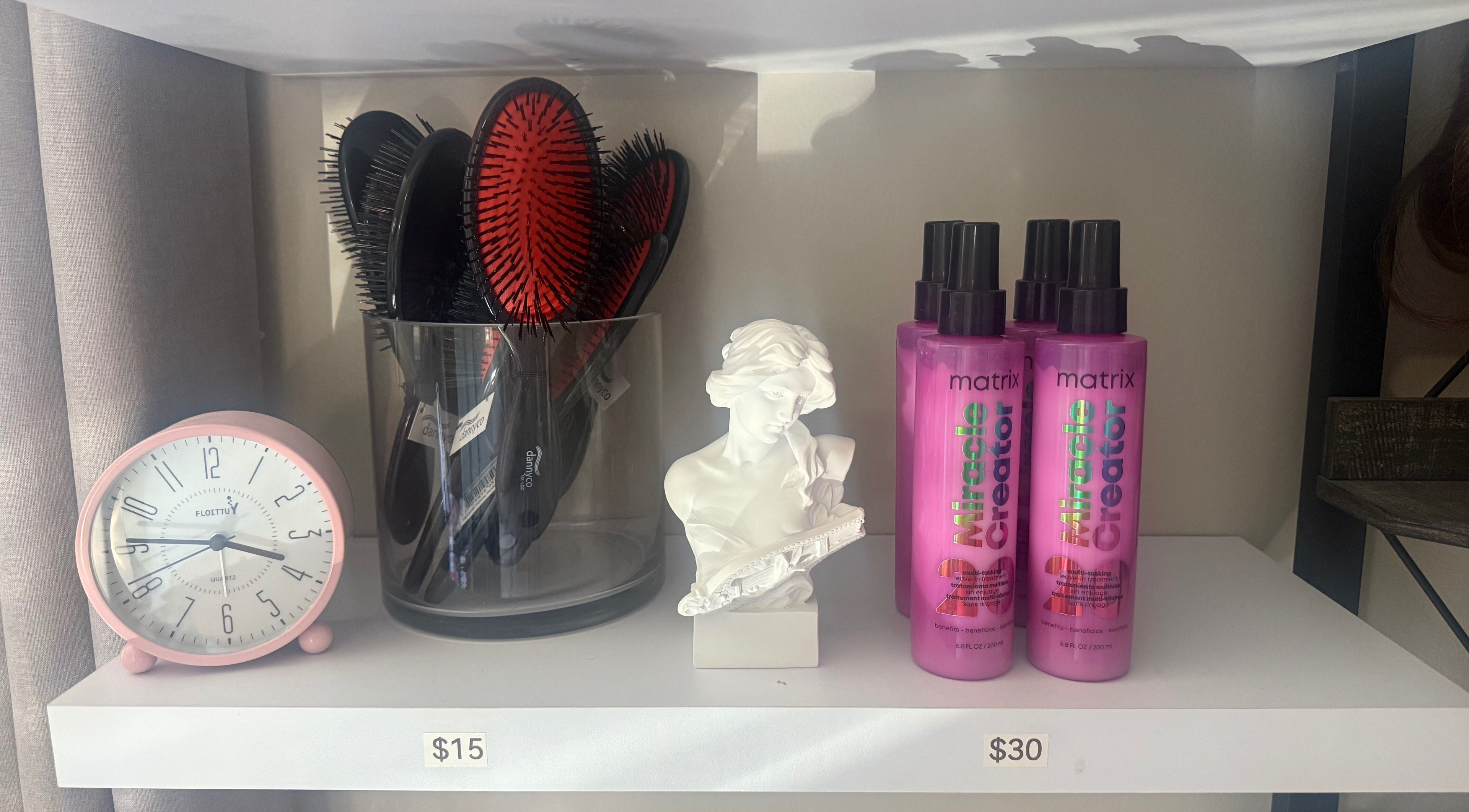 Beauty essentials at Nano Extensions by Chantelle in London, Ontario, CA. Hairbrushes, clock, and styling products on display.