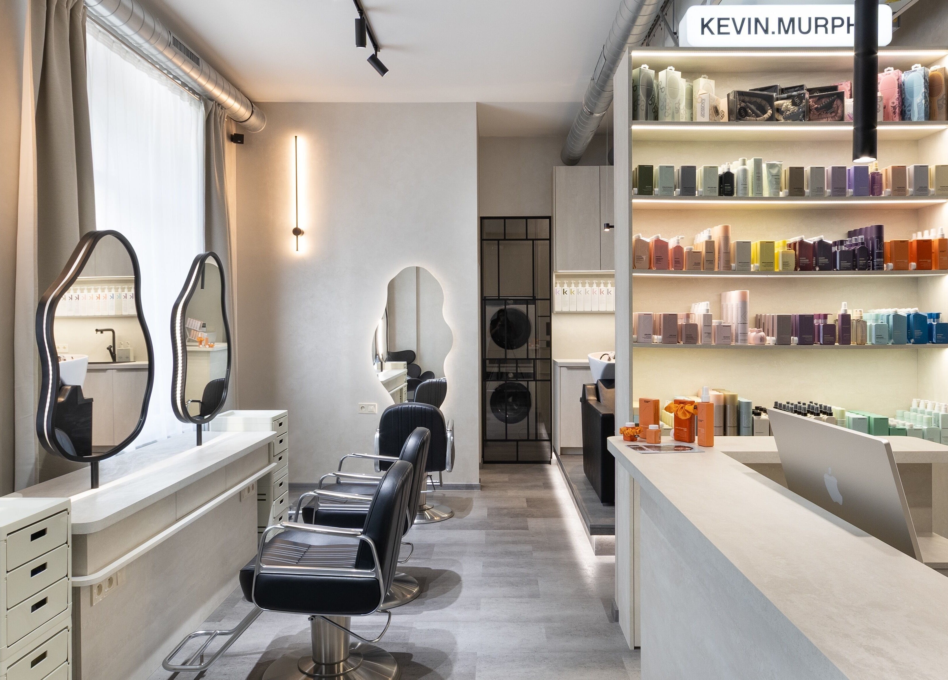 Moderní interiér salonu progress.hair v Hlavní Město Praha s elegantním nábytkem a produkty na policích.