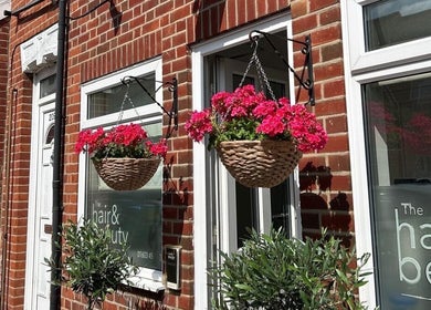 Hanging flower baskets adorn the entrance of Reflexology and Scar Release by Nadine in Norwich, England, GB.