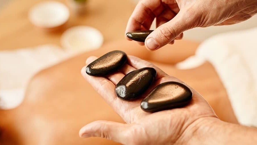 Relaxing hot stone massage at Nella Fusco LMT, CSP in Waterville, Maine, US, enhancing wellness and tranquility.