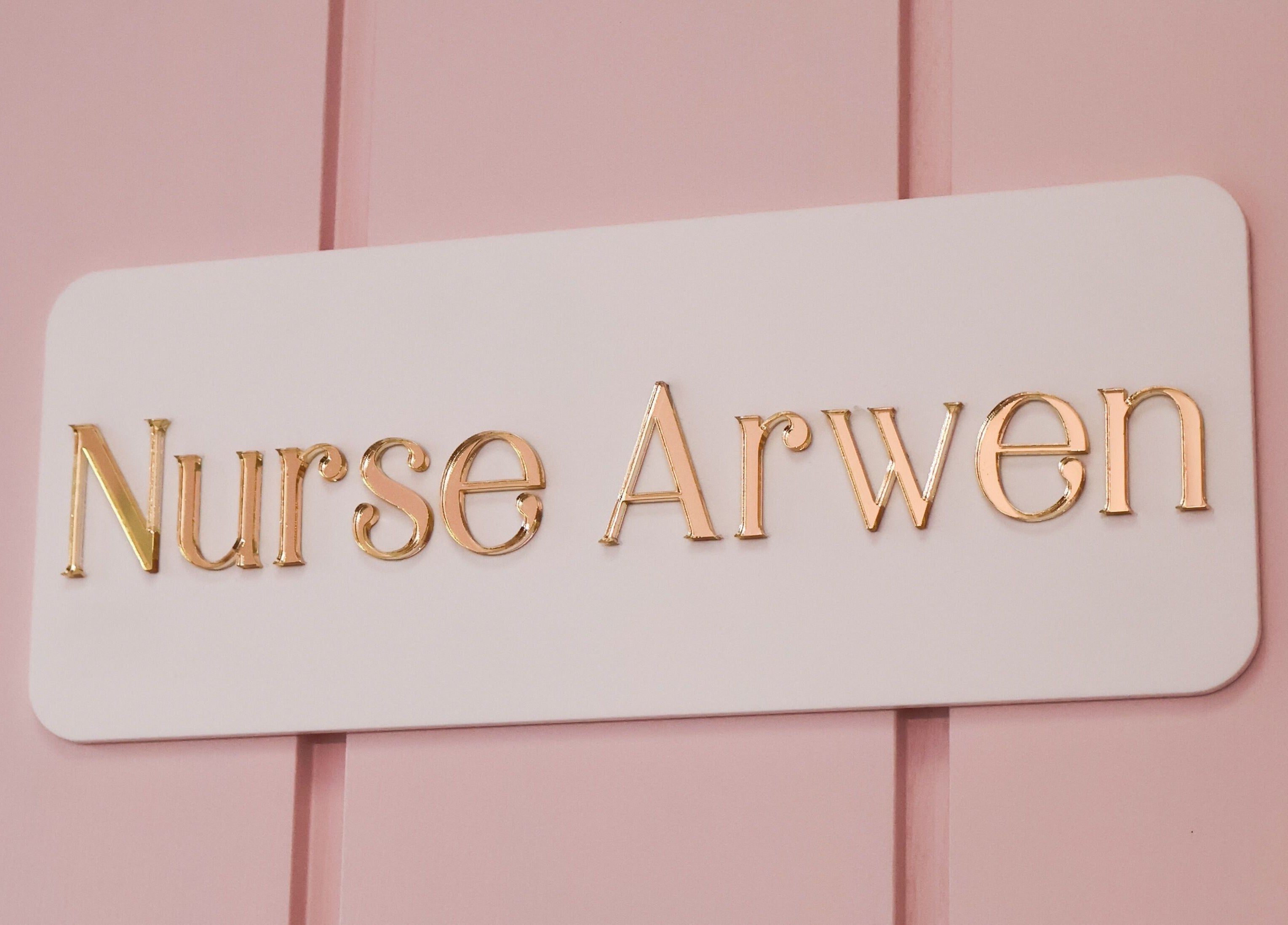 Elegant sign reading 'Nurse Arwen' at The Blossom Clinic, Beccles, England, GB, on a pink background.