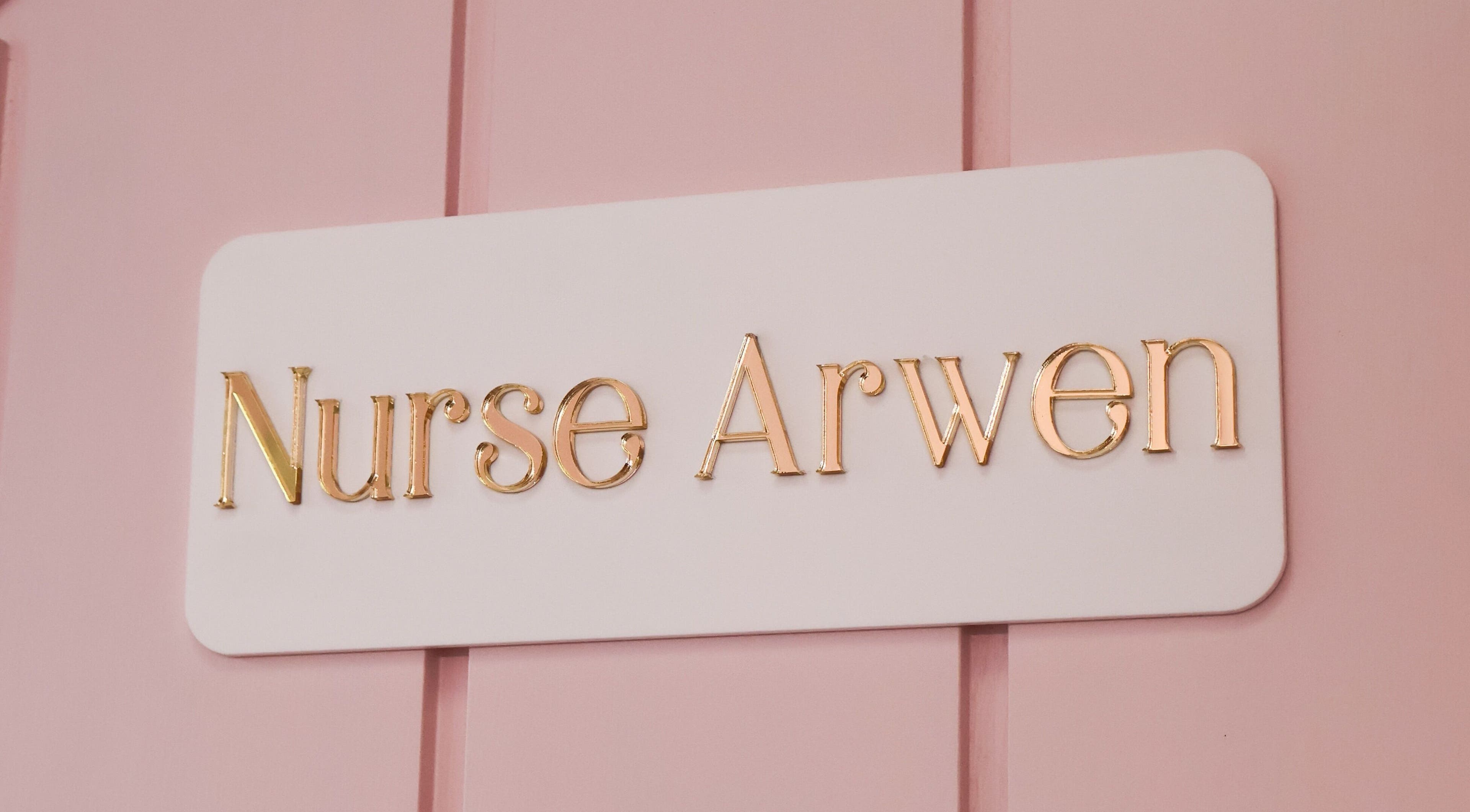 Elegant sign reading 'Nurse Arwen' at The Blossom Clinic, Beccles, England, GB, on a pink background.