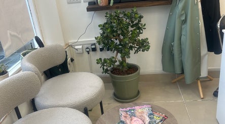 Relaxing corner at Sukhi Beauty Salon, London, England, GB with chic chairs and a potted plant.