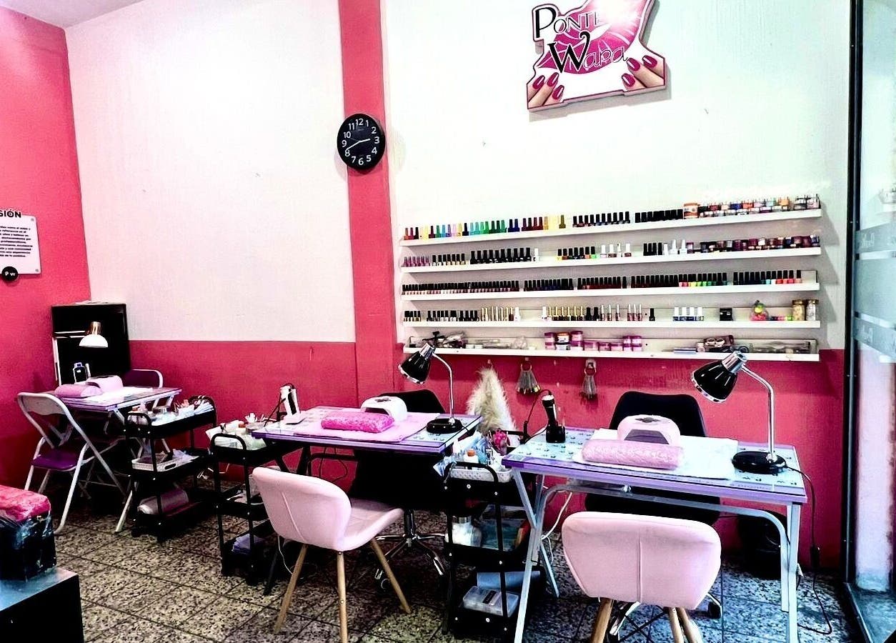 Interior moderno de Salon Pow en Quetzaltenango, GT, mostrando mesas y esmaltes coloridos.