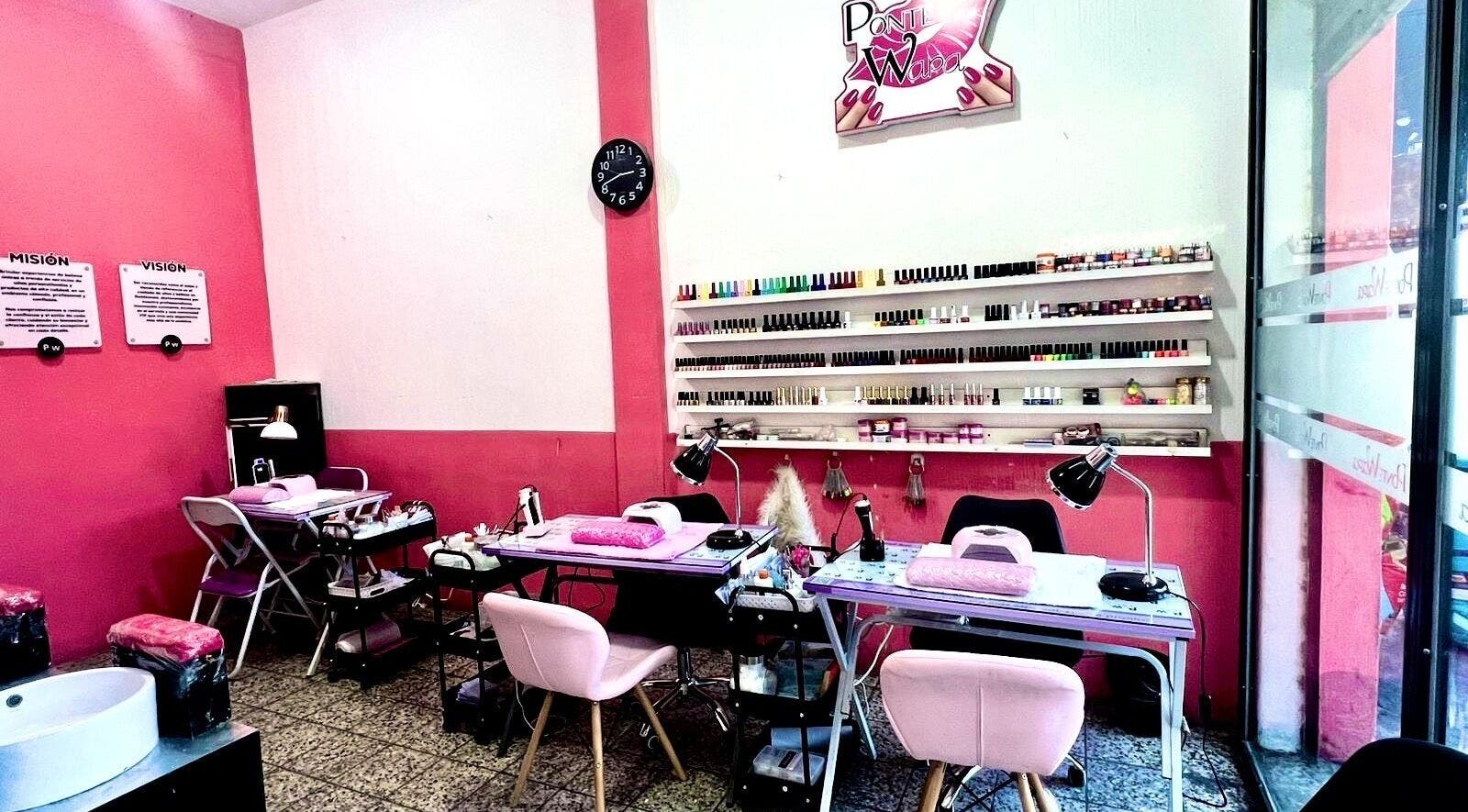 Interior moderno de Salon Pow en Quetzaltenango, GT, mostrando mesas y esmaltes coloridos.