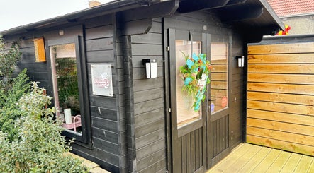 Front view of The Little Beauty Cabin in Hadston, England, showcasing a cozy and welcoming entrance.