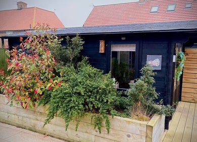 Exterior of The Little Beauty Cabin in Hadston, England, surrounded by lush greenery.