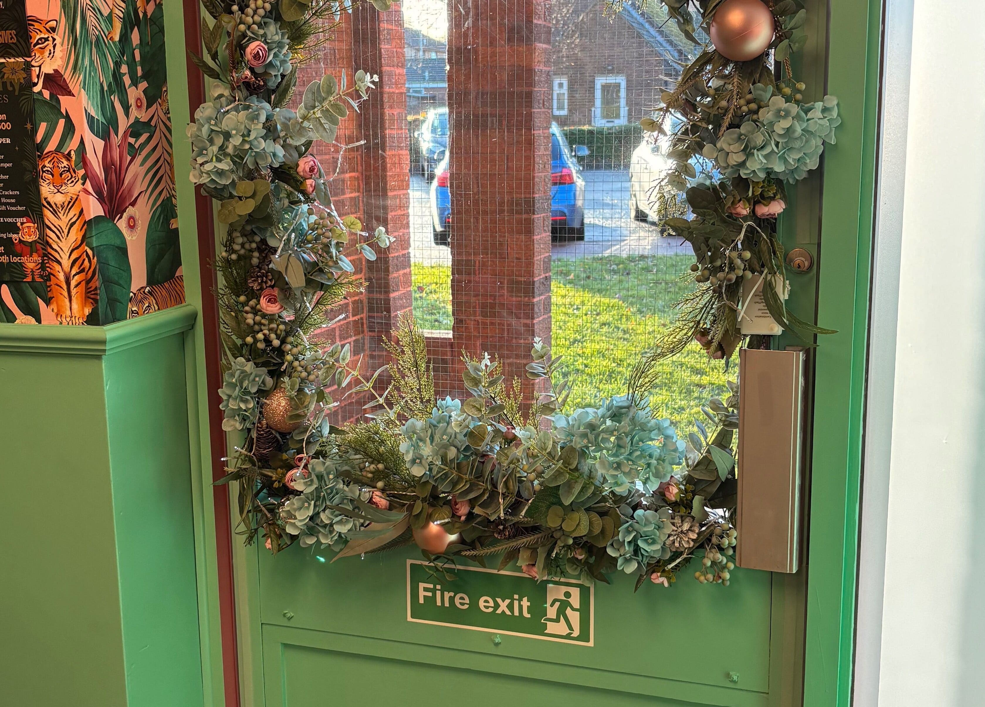 Green door with floral wreath at The Little Beauty Cabin, Hadston, England, GB, welcoming guests with elegance.