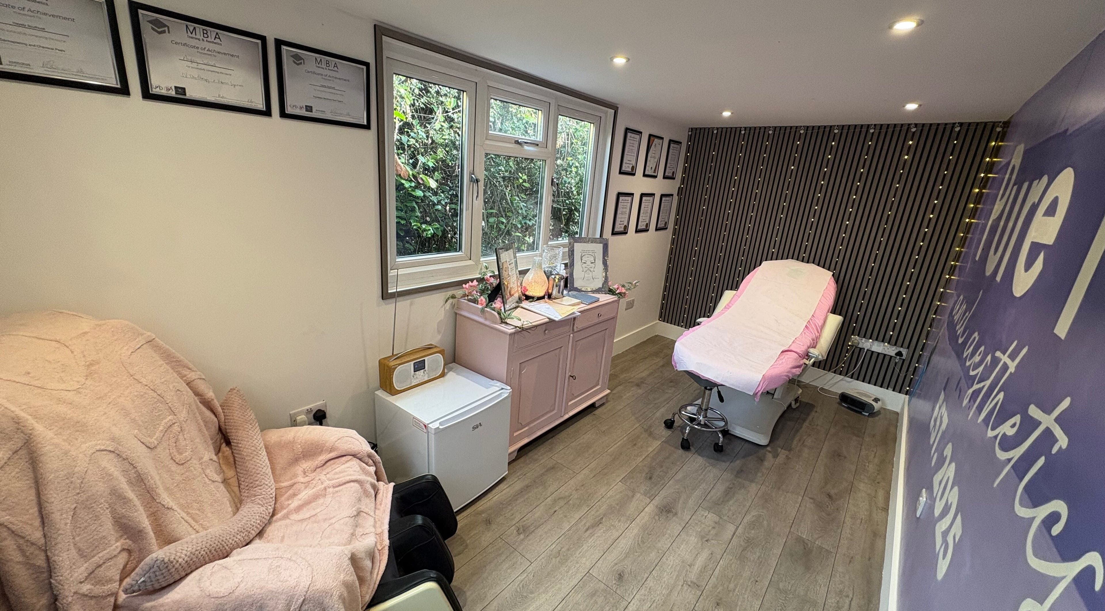 Relaxing treatment room at Pure IV and Aesthetics, Sarisbury Green, England, GB, with pink accents and certificates.