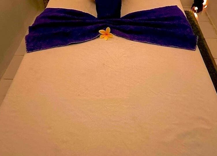 Relaxing massage table at D' Paradise SPA, Bali, Bali, ID with purple towel and yellow flower.