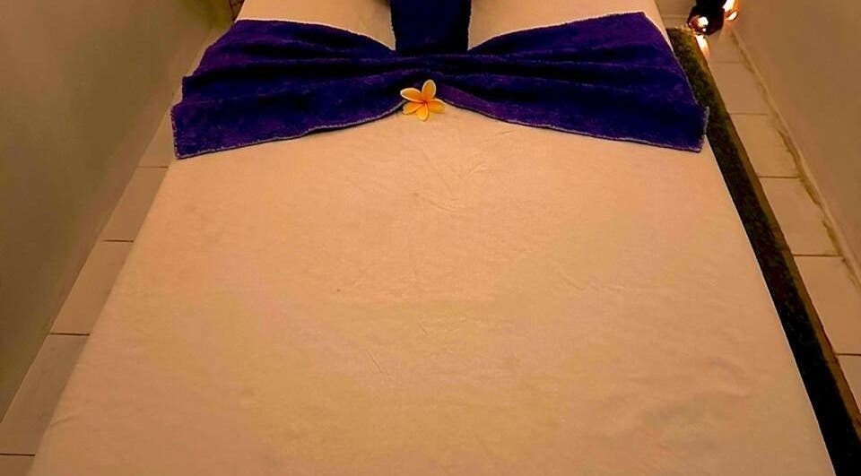 Relaxing massage table at D' Paradise SPA, Bali, Bali, ID with purple towel and yellow flower.