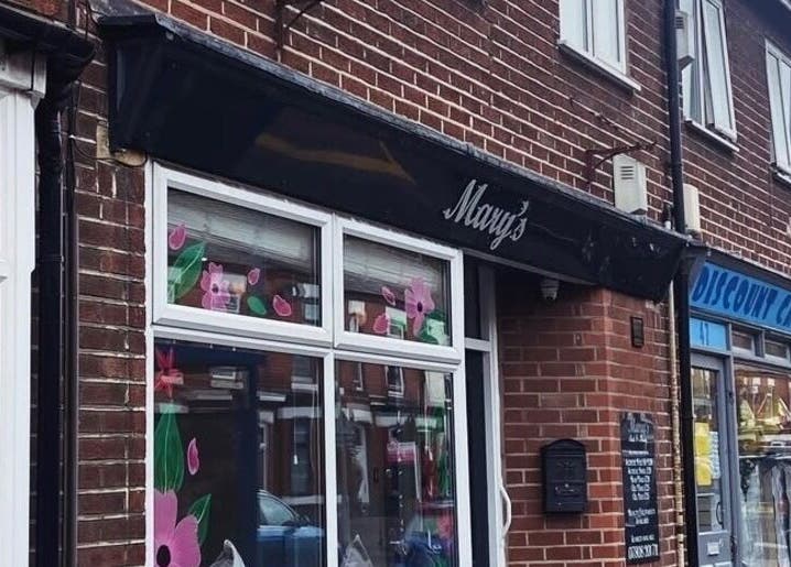 The exterior of Claws Out on a bustling street in Warrington, England, GB, showcasing floral window art.