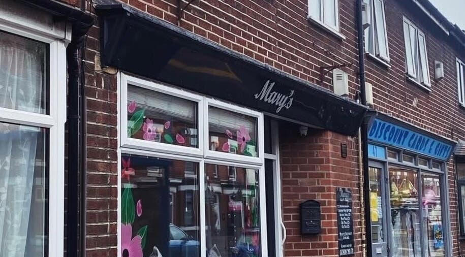 The exterior of Claws Out on a bustling street in Warrington, England, GB, showcasing floral window art.