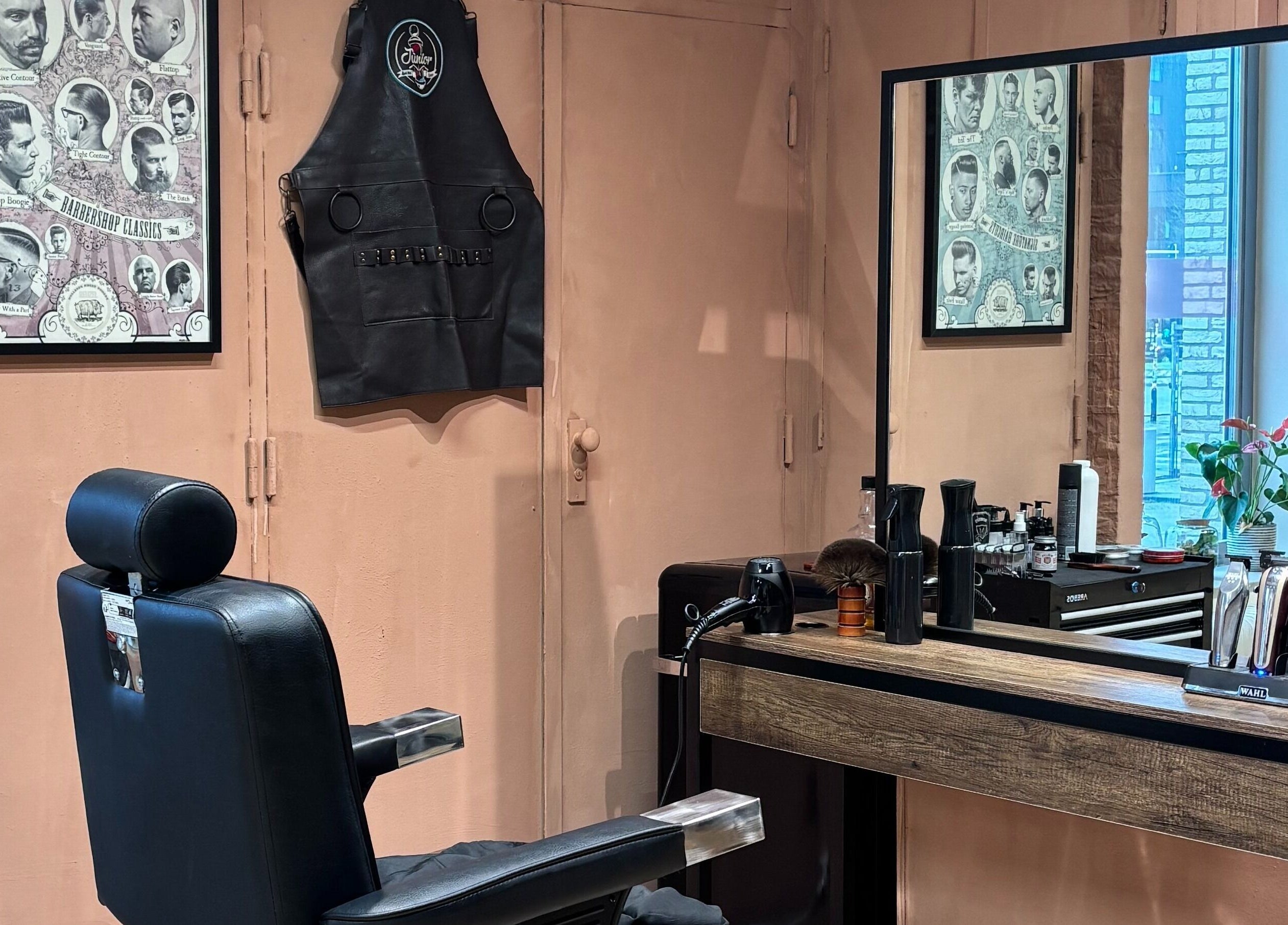 Interior da Assis Junior Barber em Eindhoven, Noord-brabant, NL. Espaço moderno com cadeira de barbeiro e espelho grande.