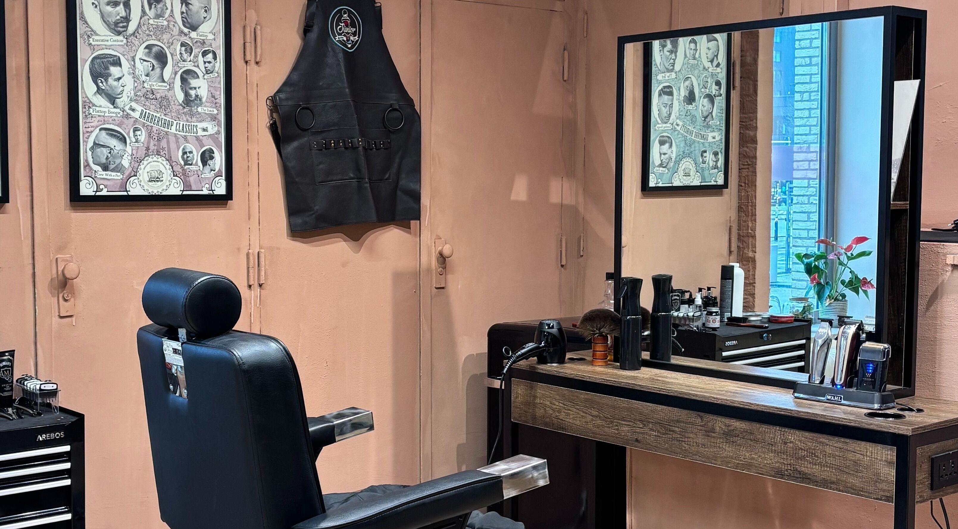 Interior da Assis Junior Barber em Eindhoven, Noord-brabant, NL. Espaço moderno com cadeira de barbeiro e espelho grande.