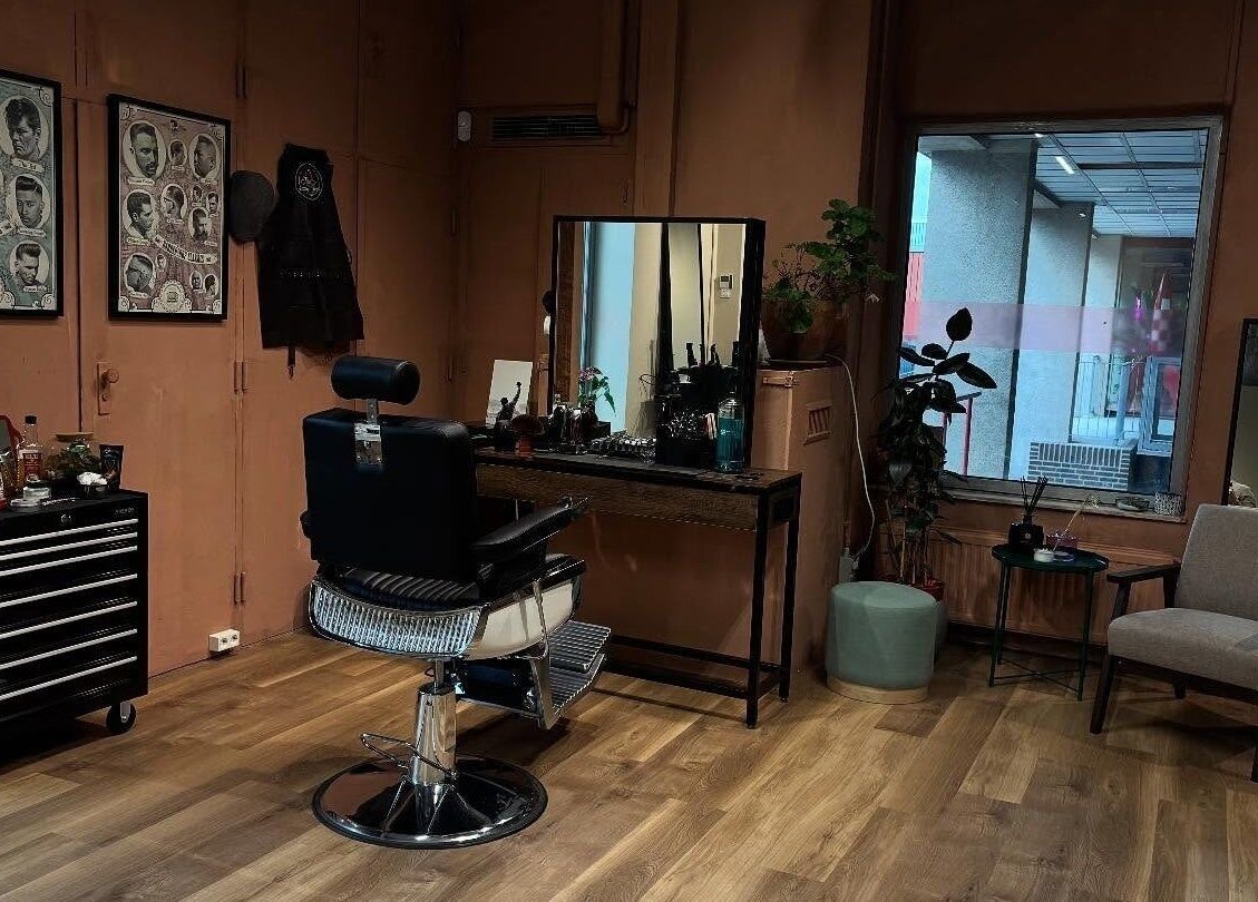 Interior da Assis Junior Barber, Eindhoven, Noord-brabant, NL, com cadeira e decoração clássica.