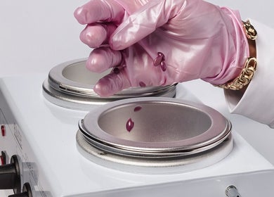 Pink-gloved hand preparing wax at Wax & Glow Studio, Allentown, Pennsylvania, US.