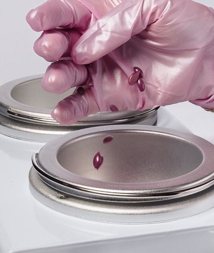 Pink-gloved hand preparing wax at Wax & Glow Studio, Allentown, Pennsylvania, US.
