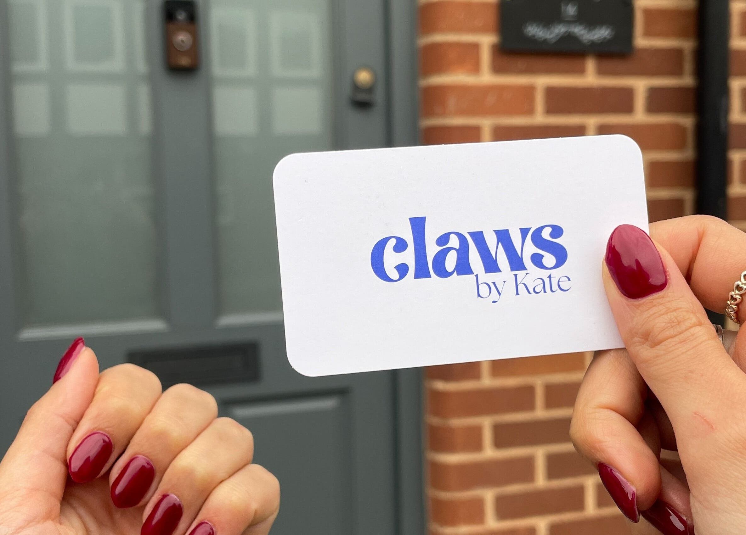 Hand with red nails holding Claws By Kate card at Knowle, England, GB entrance.