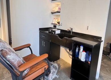 Modern barber station at Mr Boombastic, Sib, Muscat Governorate, OM with sleek black counter and leather chair.