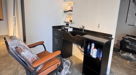 Modern barber station at Mr Boombastic, Sib, Muscat Governorate, OM with sleek black counter and leather chair.