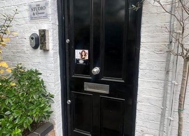 Entrance to The Skin Sculptress in Richmond, England, GB with black door and greenery.