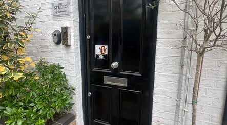 Entrance to The Skin Sculptress in Richmond, England, GB with black door and greenery.