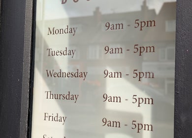 Woof & Sip Dog Spa hours displayed on glass, Moreton, England, GB, Monday to Friday, 9am-5pm.