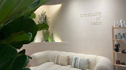 Relaxing lounge at Creature Of Habit, Singapore, SG with plush seating, green plants, and elegant decor.