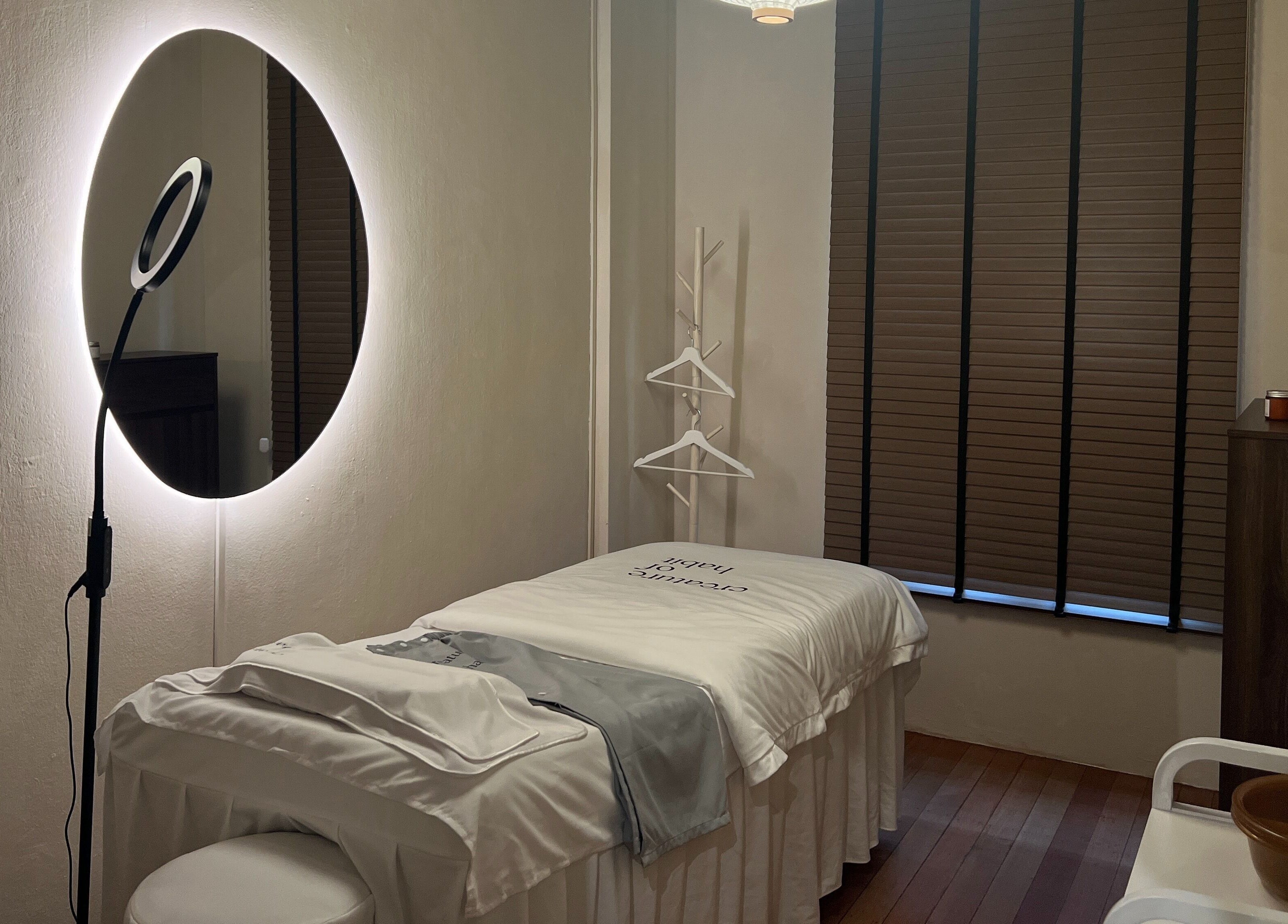 Relaxing treatment room at Creature Of Habit, Singapore, SG, featuring a cozy bed and ambient lighting.