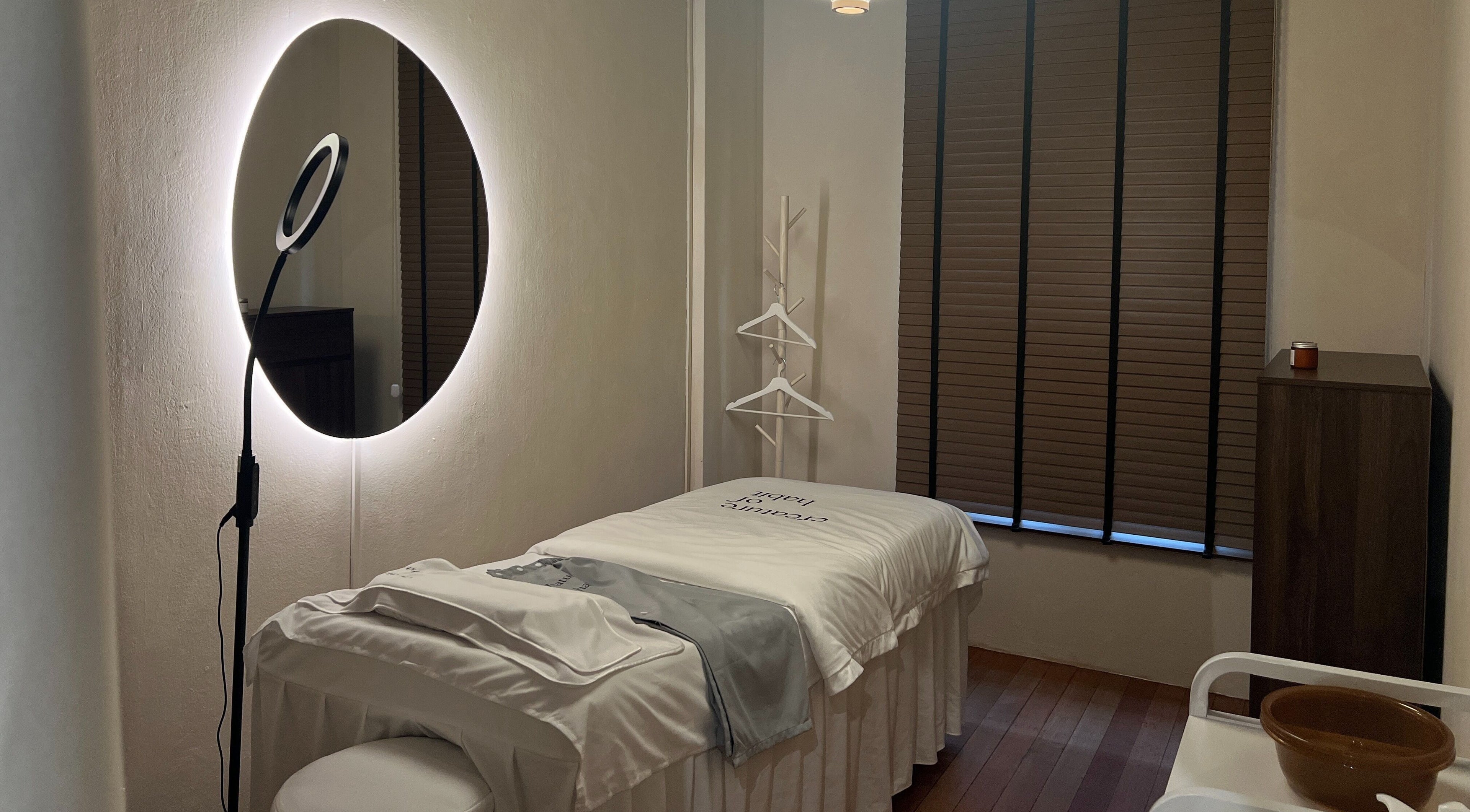 Relaxing treatment room at Creature Of Habit, Singapore, SG, featuring a cozy bed and ambient lighting.