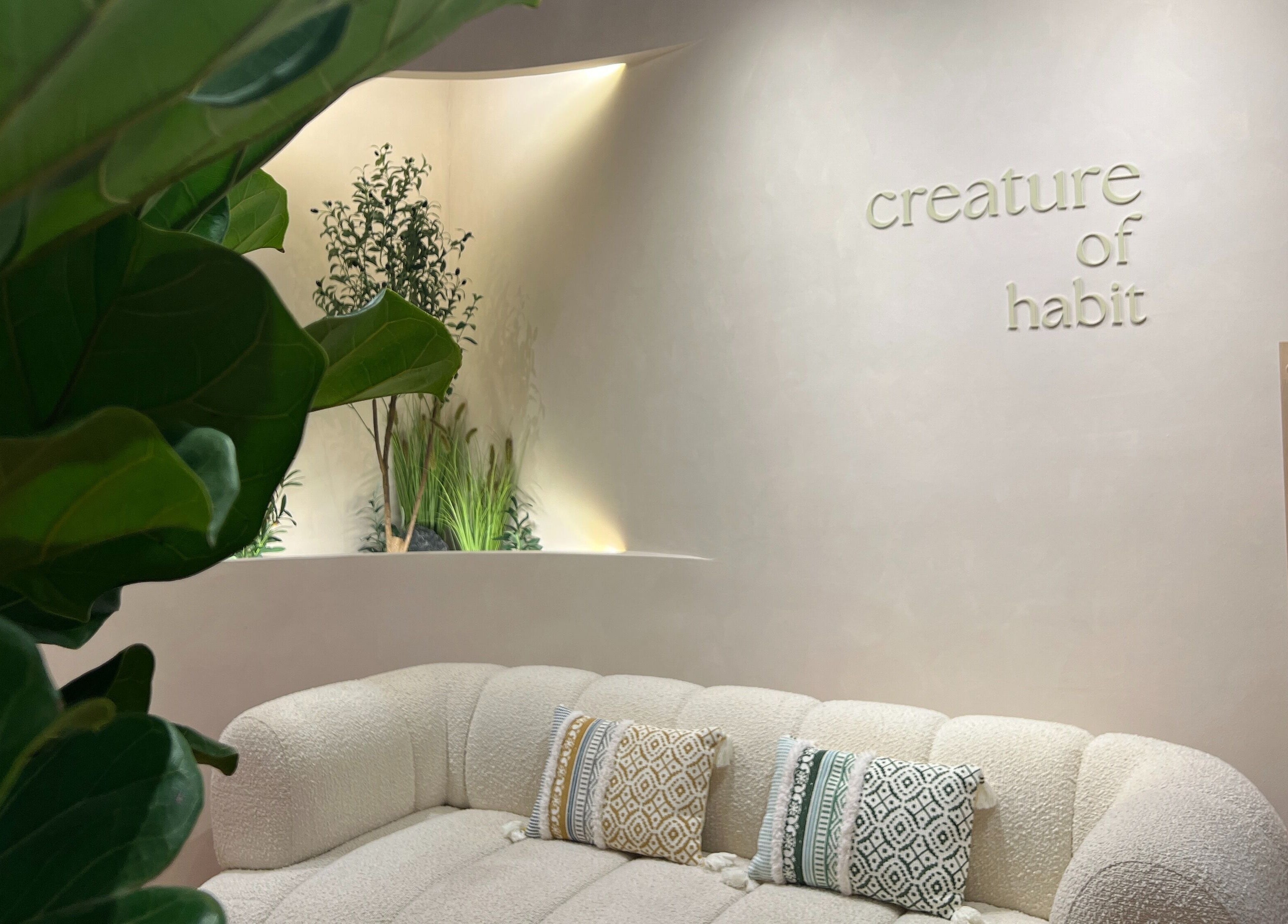 Elegant lounge at Creature Of Habit, Singapore, SG, with cozy sofa and greenery.