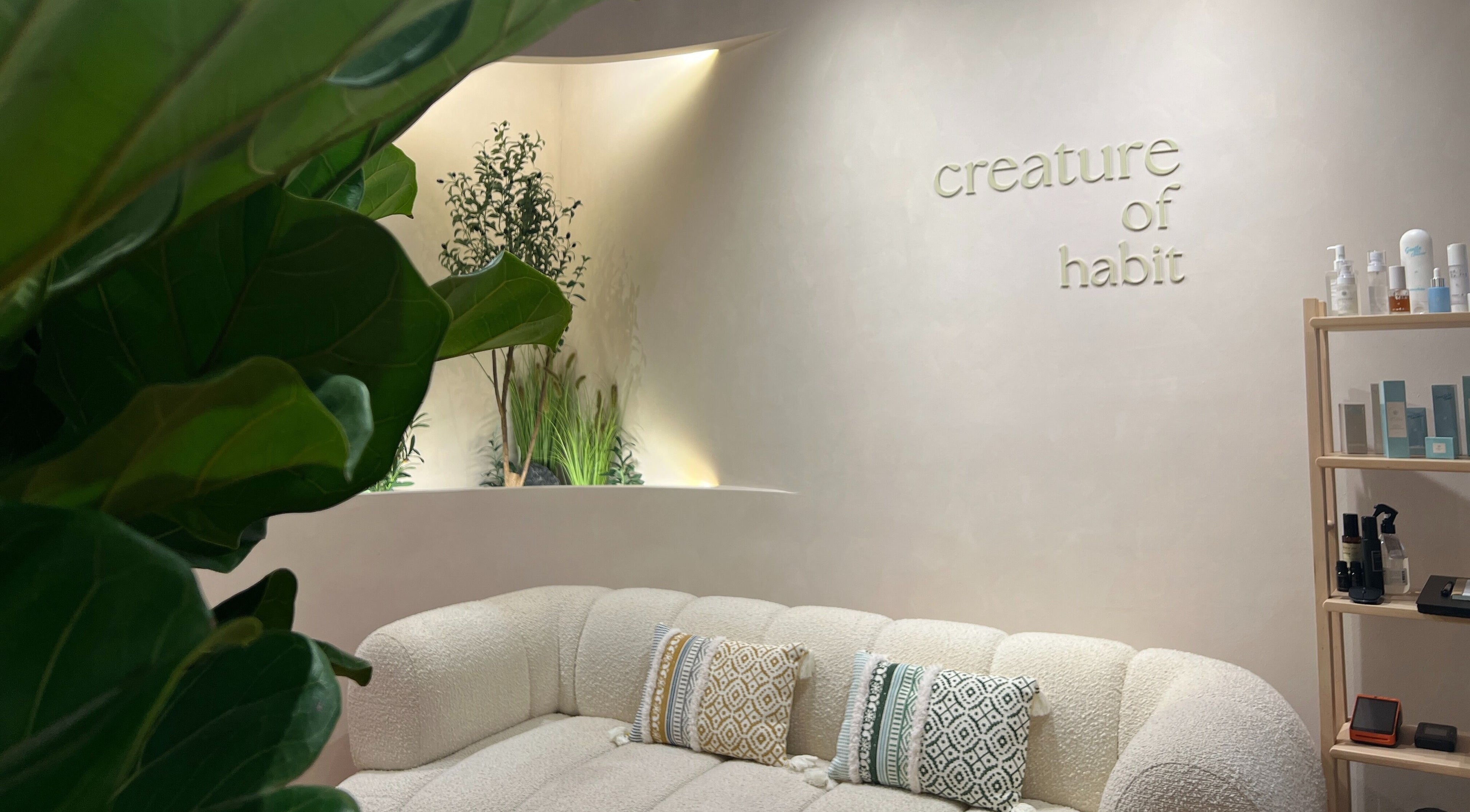 Elegant lounge at Creature Of Habit, Singapore, SG, with cozy sofa and greenery.
