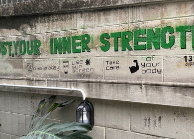 Green mural at 139Arena, Krung Thep Maha Nakhon reading 'Trust Your Inner Strength,' promoting wellness.