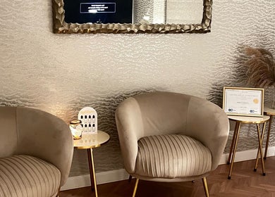 Elegant waiting area in nailsbyreb_ at Bishopbriggs, Scotland, GB with plush armchairs and gold accents.