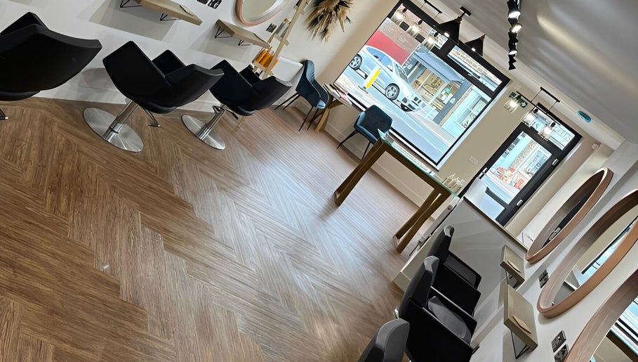 Elegant salon interior at Hair By HM at Chique, Mapplewell, England, GB, displaying modern styling chairs and mirrors.